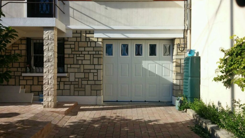 Porte garage coulissante blanche hublots facade pierre pose sur mesure