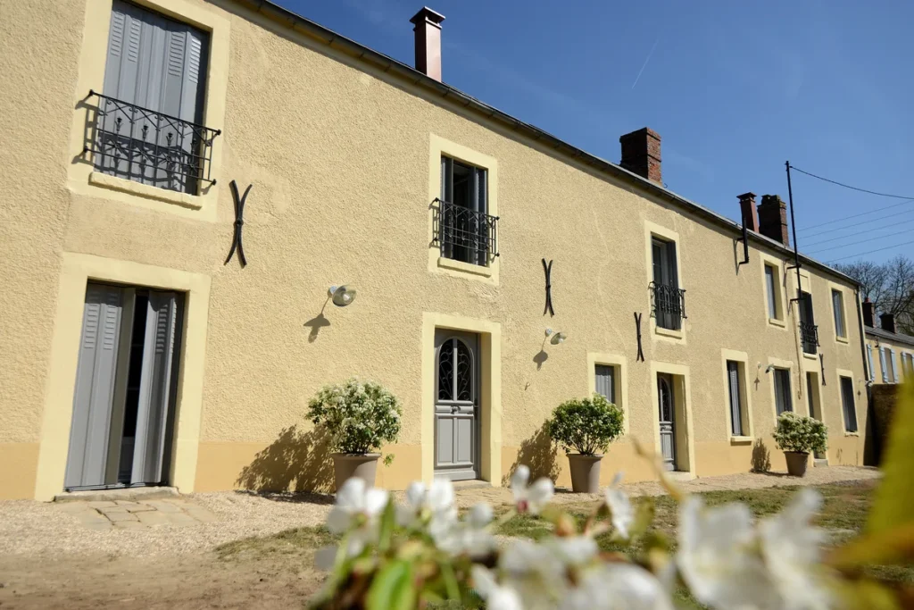 Jalousies aluminium grises sur mesure sur les fenêtres et portes d'une longère à façade ocre