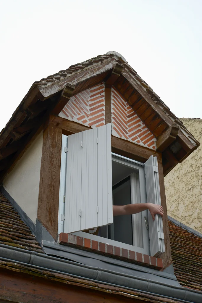 Persienne bois repliable gris clair sur mesure, lucarne à colombages et briques