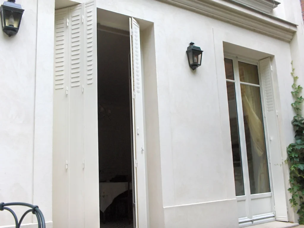 Persiennes fer repliables blanches sur mesure, repliées dans le tableau, façade blanche avec lanternes