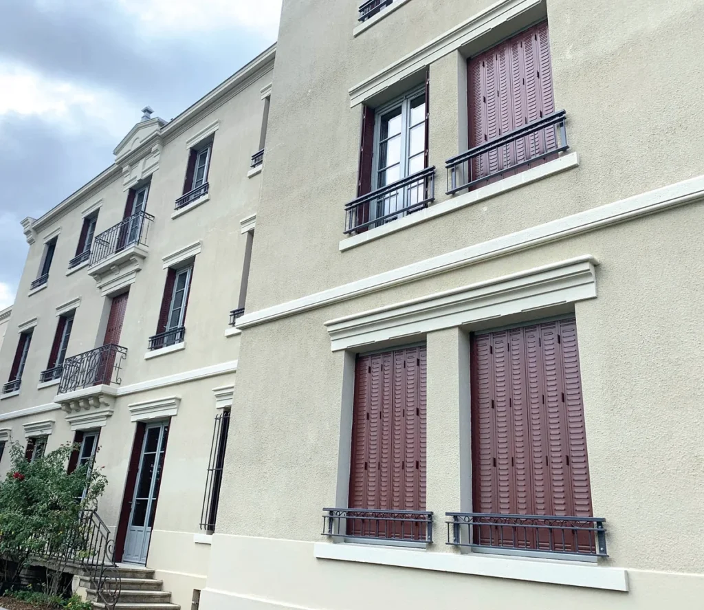 Persiennes fer repliables rouge brun sur mesure, immeuble ancien rénové avec garde-corps