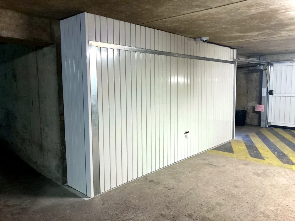 Porte de garage basculante blanche sur mesure avec imposte en tôle au-dessus et sur le côté, parking souterrain — photo de réalisation client (Montigny-lès-Cormeilles, Val-d'Oise)