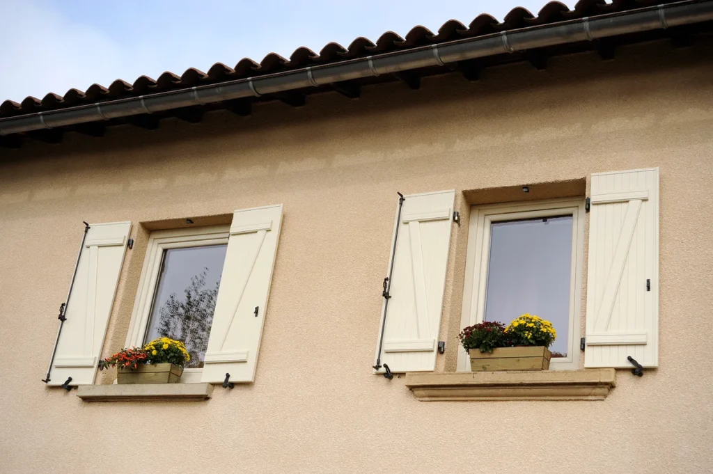 Volets battants PVC blancs à barres et écharpes sur mesure, fenêtres fleuries
