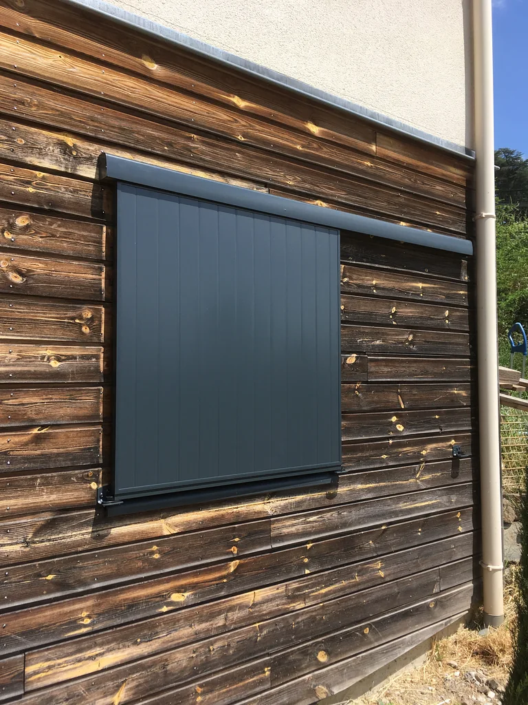 Volet coulissant aluminium gris anthracite sur mesure sur une façade en bardage bois