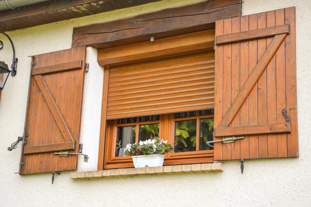 Volet roulant aluminium chêne doré sur mesure, à moitié baissé, entre deux volets en bois
