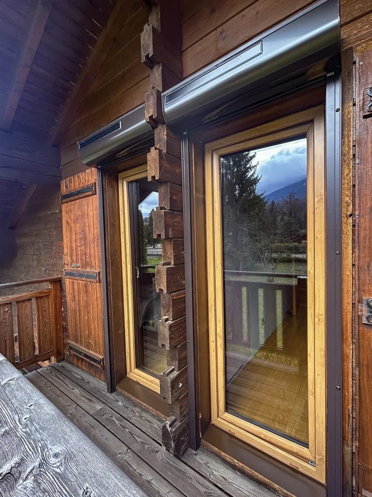 Volets roulants solaires gris sur mesure sur les portes-fenêtres d'un chalet en bois